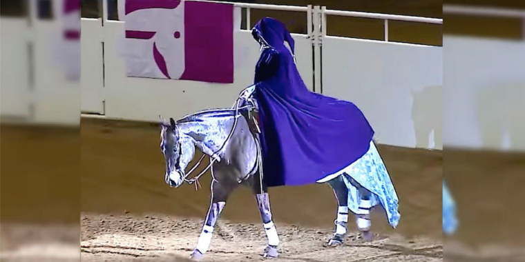 Hun rider langsomt ind på scenen, men så fjerner hun sin kappe og forbløffer alle
