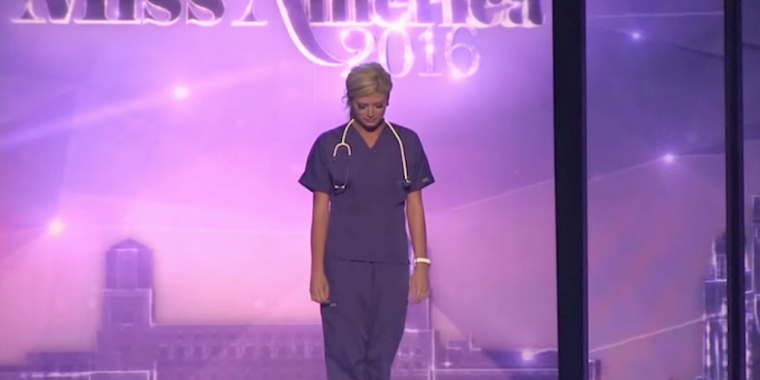 Skønhedsdronning træder frem på scenen klædt som sygeplejerske, kigger op og forbavser alle
